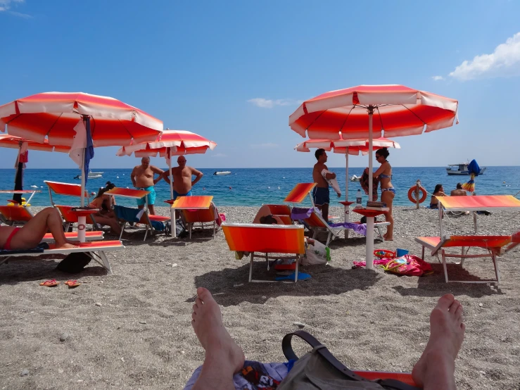 there are people sitting in lounge chairs on the beach