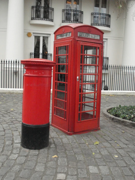 two red telephone booths on a brick paved road