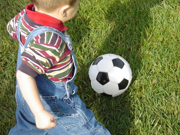 a young child standing next to a soccer ball