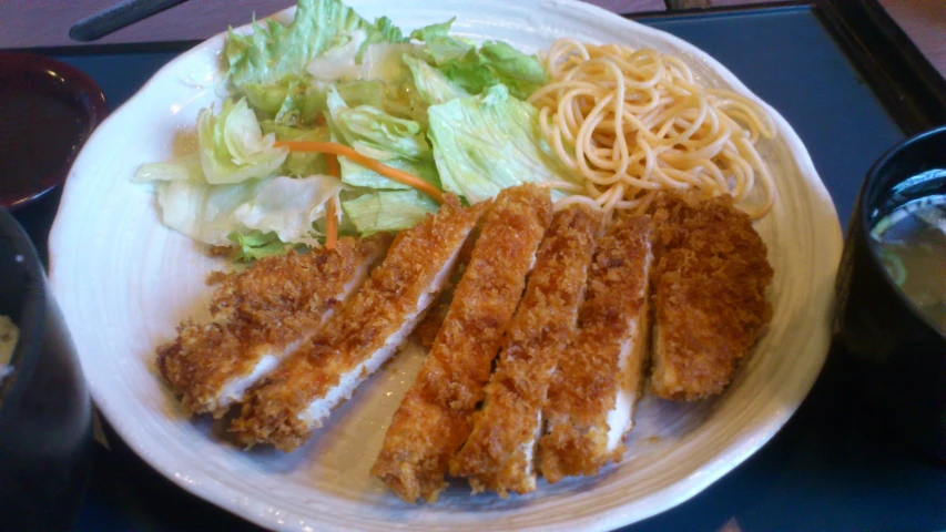 a plate of noodles and lettuce and chicken with sauce