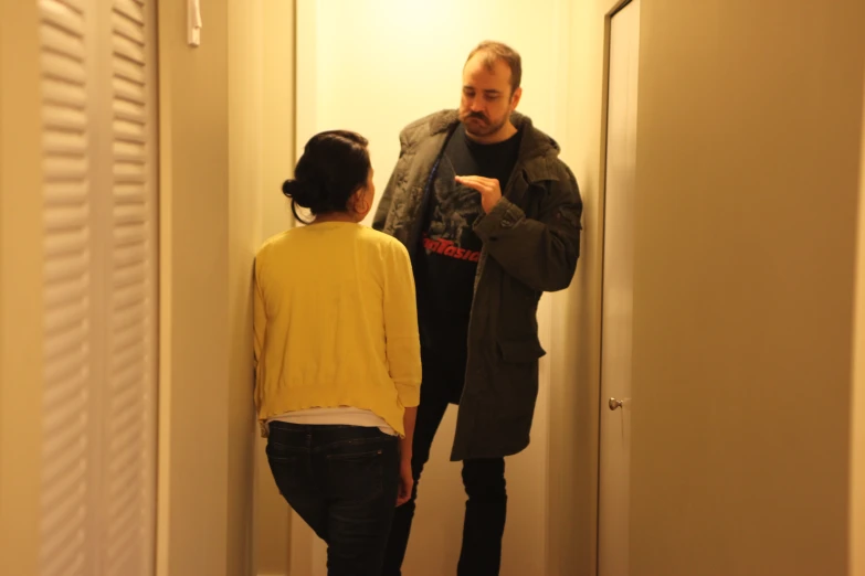 two men are standing in the hallway pointing towards the door