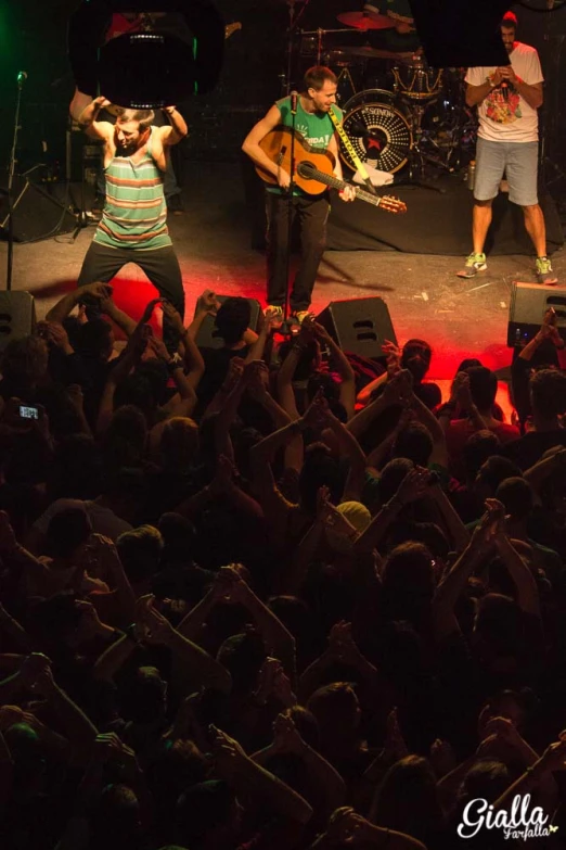 three men singing on stage while holding instruments