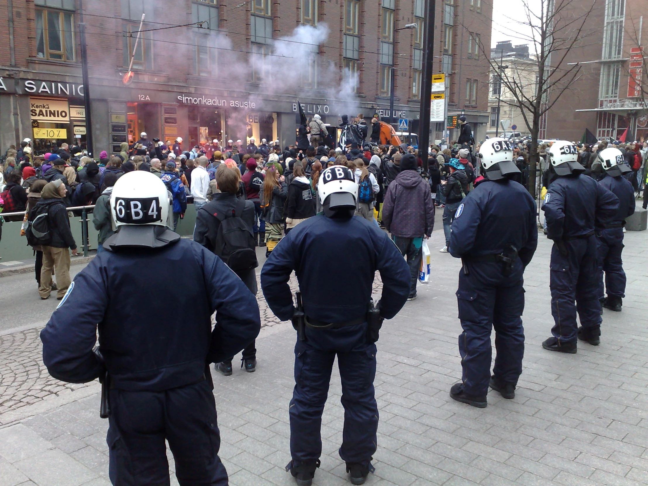 police stand on the street while protesters march in protest