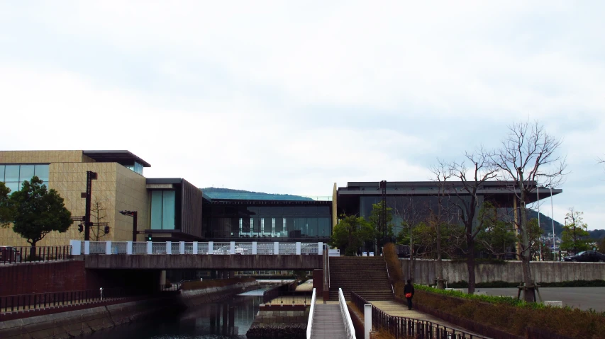 people walk over a concrete walkway next to water