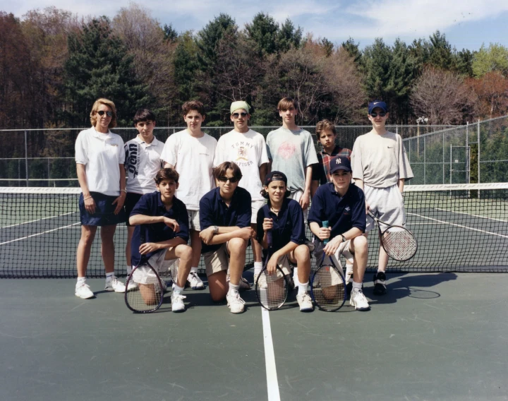 a group of people standing on top of a tennis court