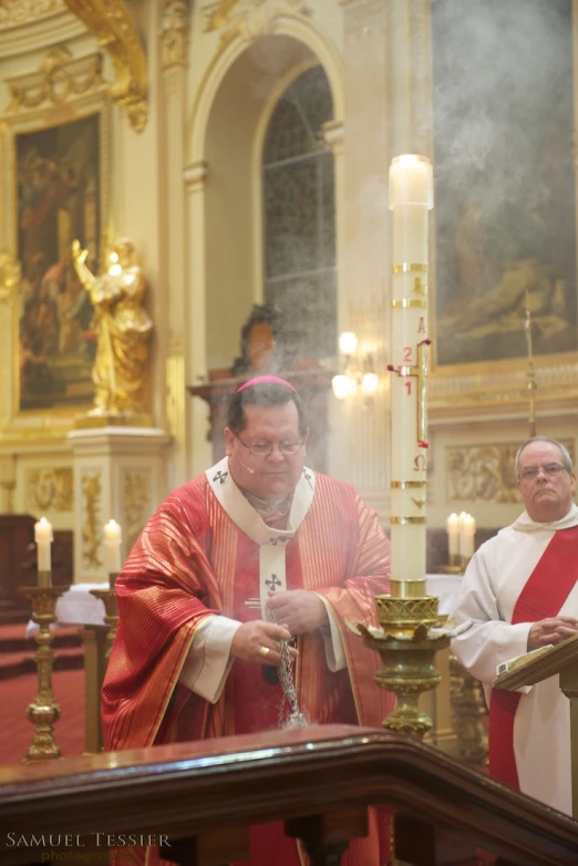 a priest prepares to sing in front of a podium with candles in the background