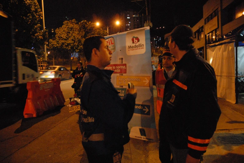 two men standing next to each other while talking on the side of the road