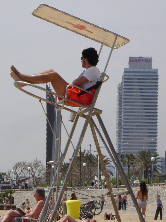 a man sitting in a chair at the beach next to a lifeguard tower