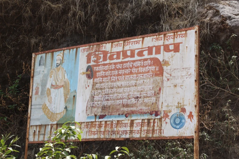 a sign sits among vegetation with an interesting painting