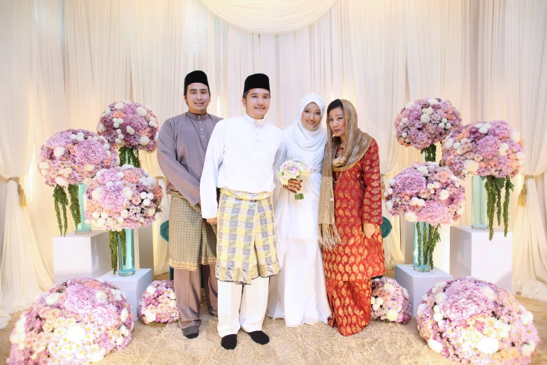 four people posing for a picture while dressed up in traditional indian attire