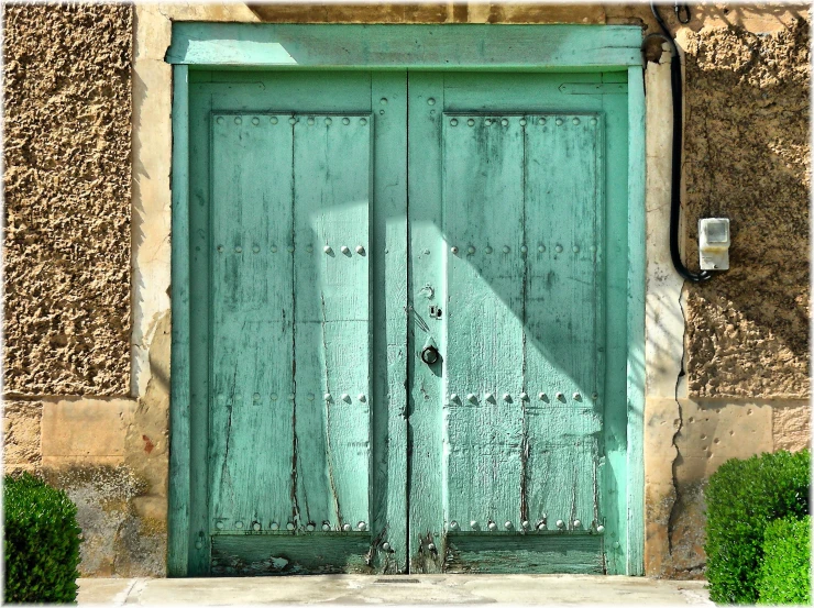 a green door to an old building with a clock on it