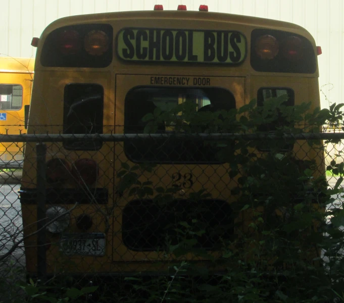 a school bus sits in a yard behind a chain link fence