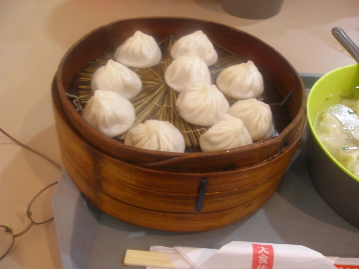 a wooden bowl of dumplings on a plate with chopsticks and chop sticks