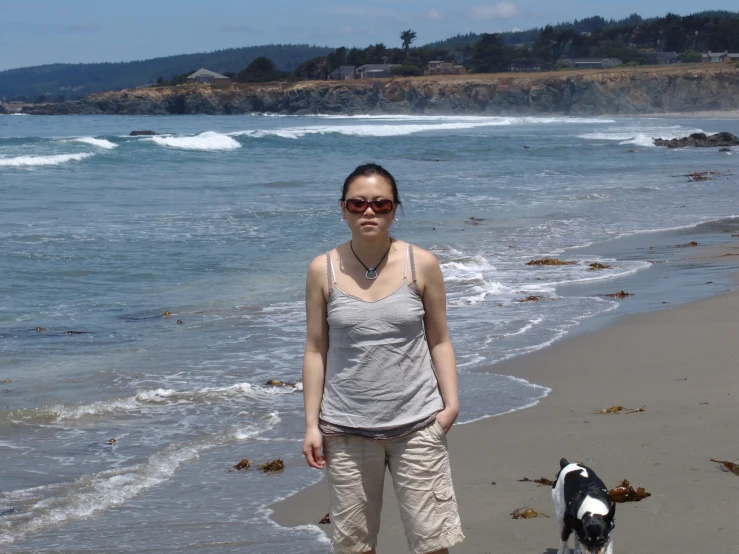 a woman with her black and white dog on a beach