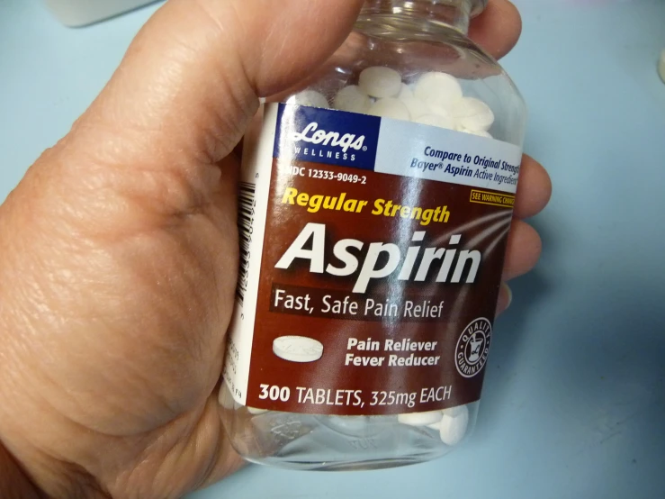 a person holds a jar of aspiin in their hand