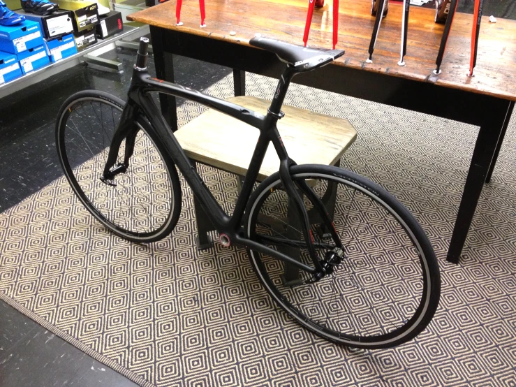 a black bike is sitting in front of a wooden table