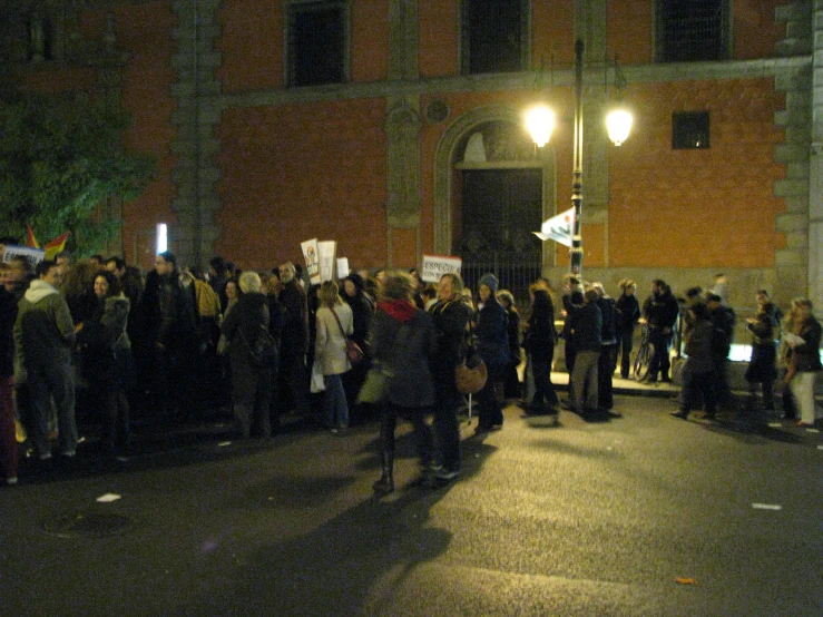 a large crowd with sign protestors near a building