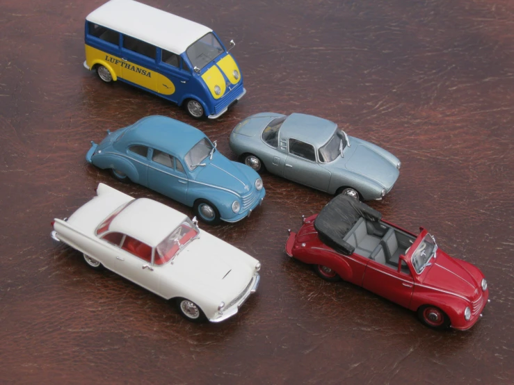 four toy cars are placed on a wooden table