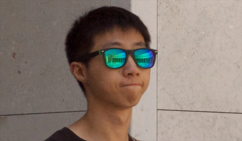 a young man wearing blue and green mirrored sunglasses