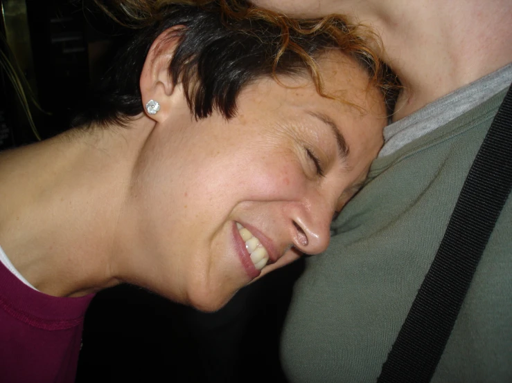 a woman smiles while holding her face to her back