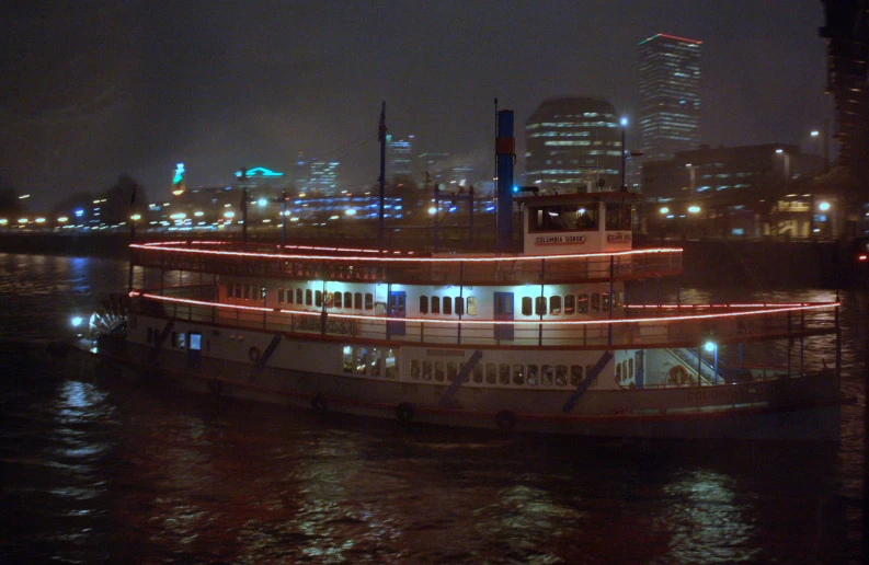 a ferry at night with a large cityscape