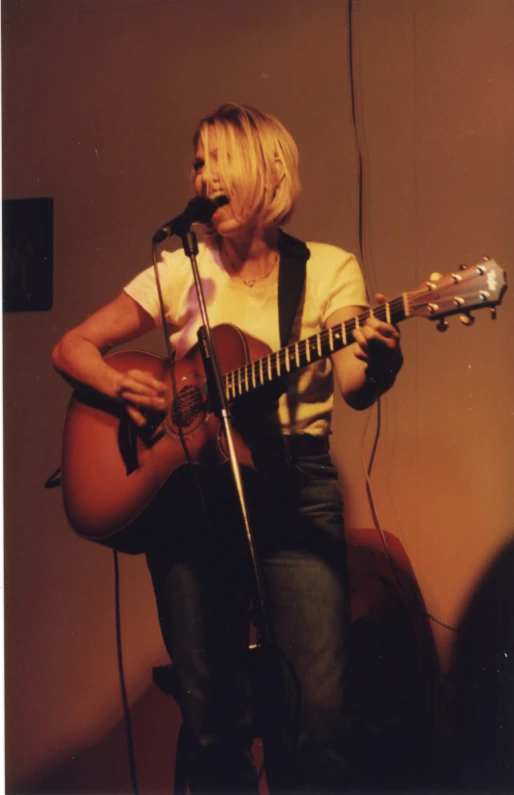 a woman plays the guitar in front of a microphone