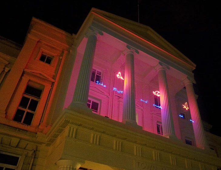 an old building is lit up in pink light