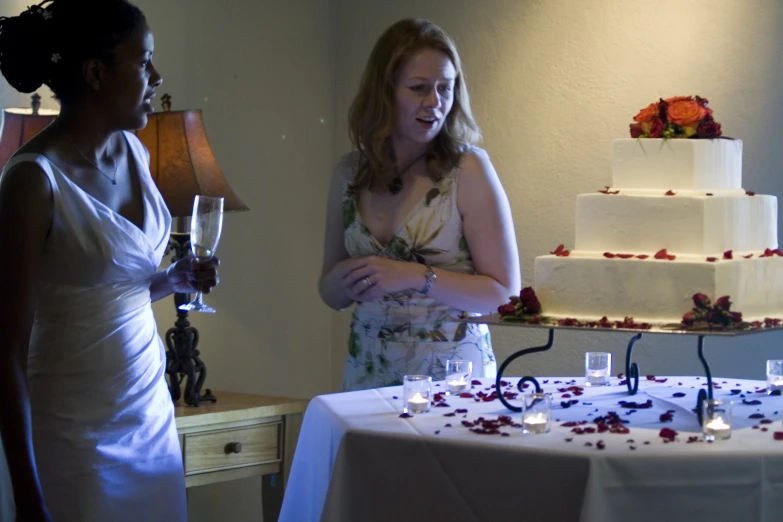 two women standing by a table with a cake