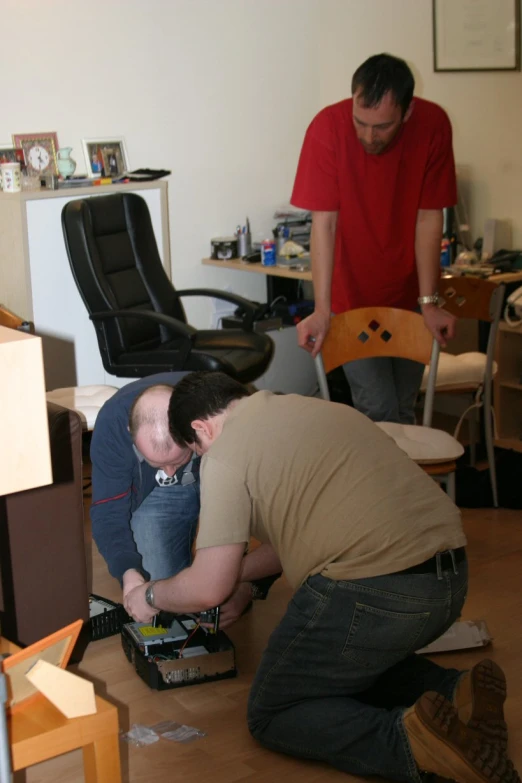 a man working on a piece of furniture with another man watching