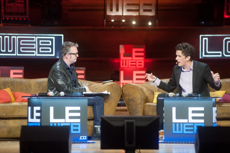 two men sitting on stage talking to each other