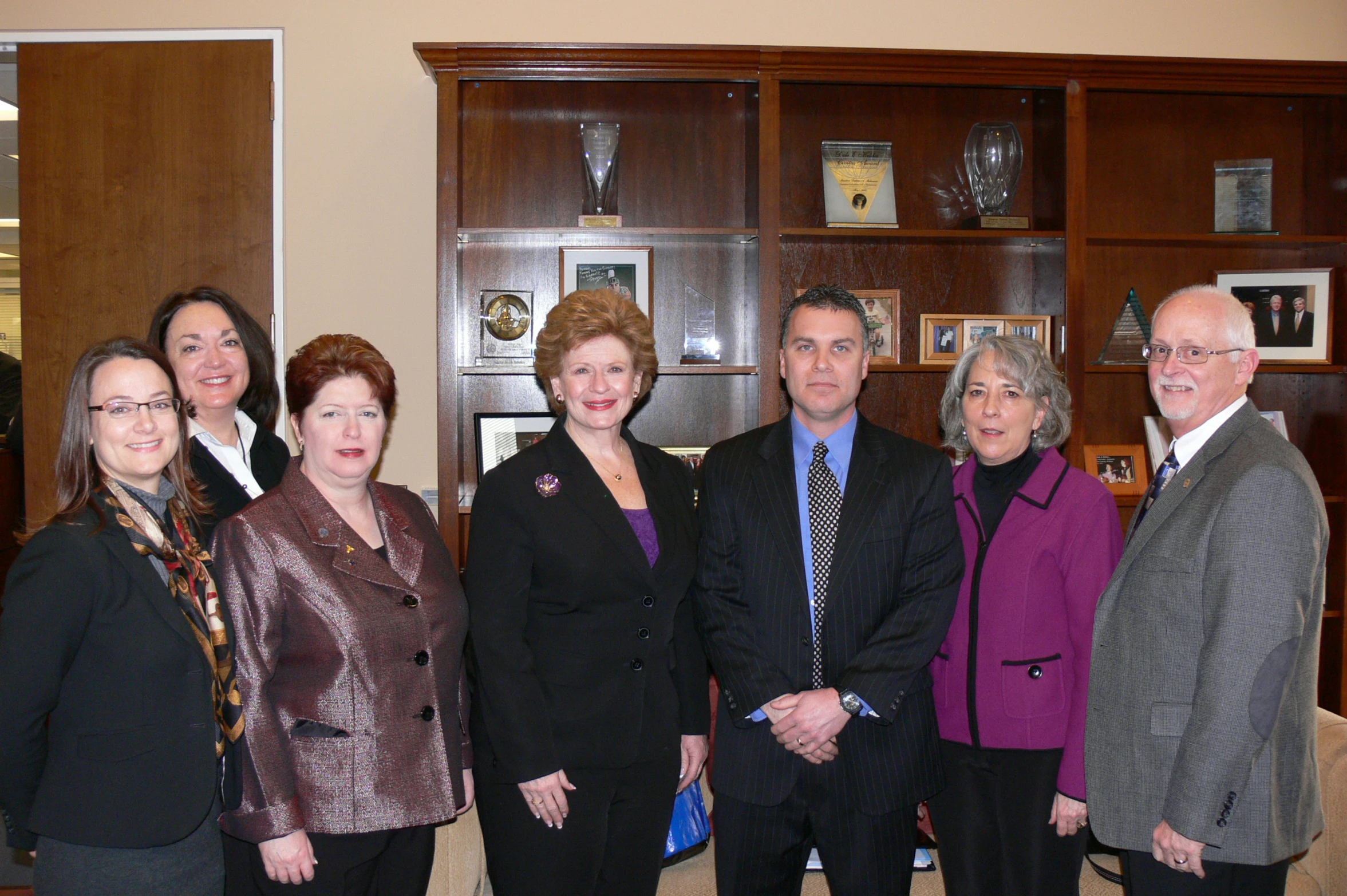 several business people pose for a picture in front of cabinets