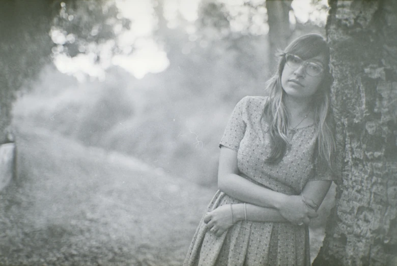 a woman leaning against a tree in the forest