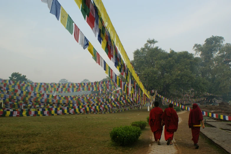 two men in red are walking up to a wall with colorful flags in the background