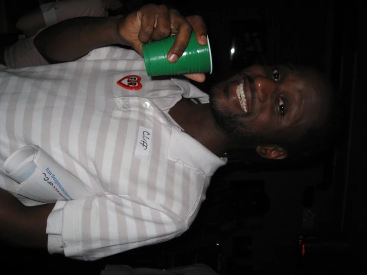 a smiling man holding a green cup in his hand