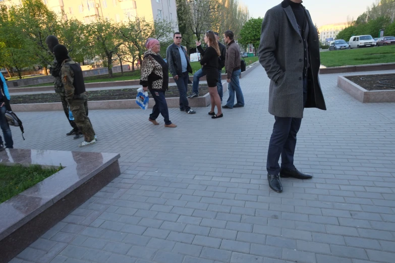 people standing on the sidewalk as one man talks on his cell phone