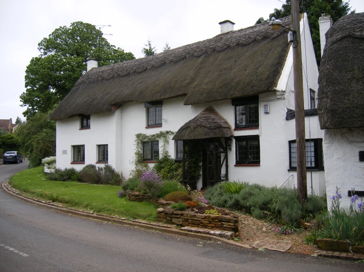 a white cottage sitting next to the side of a road