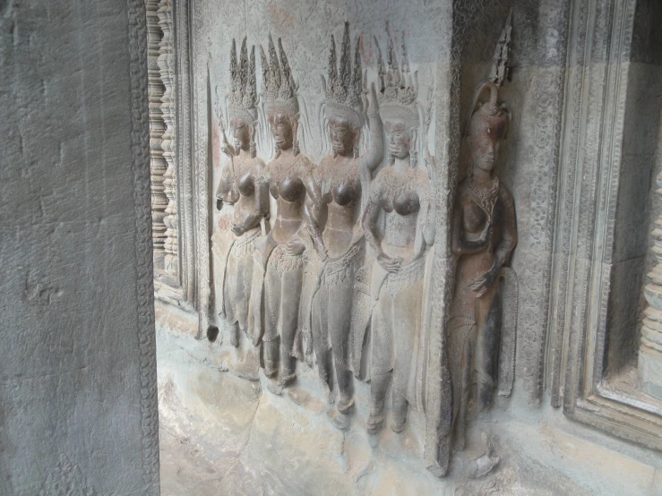 a carved relief of women holding head, standing on one side of the wall and looking down