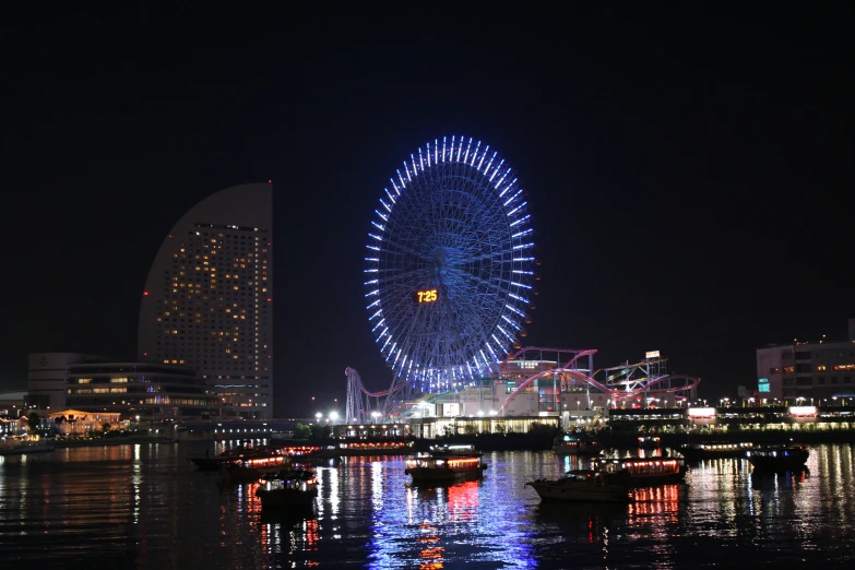 a large ferris wheel over looking a city by night