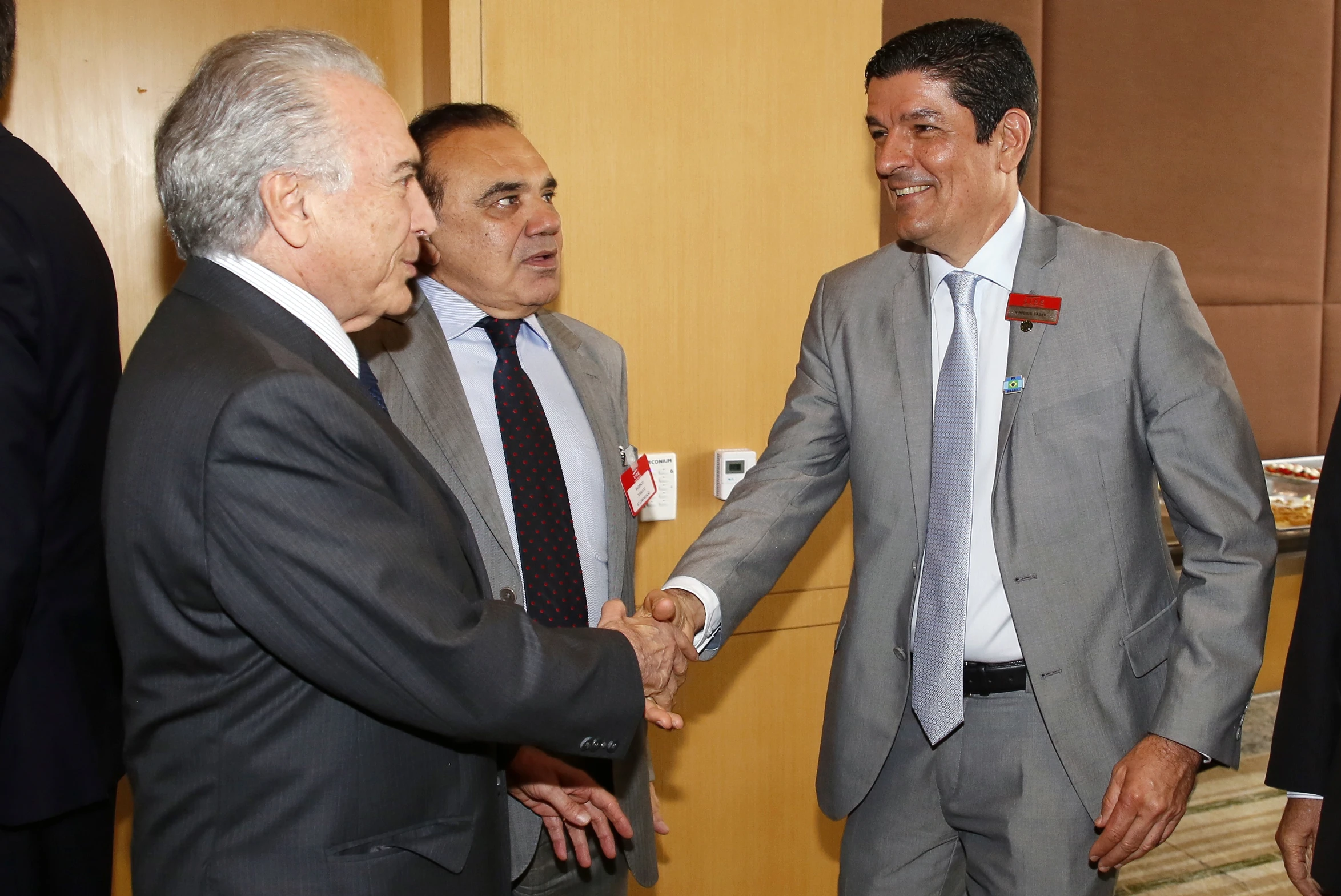 a group of three men in suits shaking hands