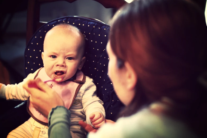 a baby eating some food in its mother's lap