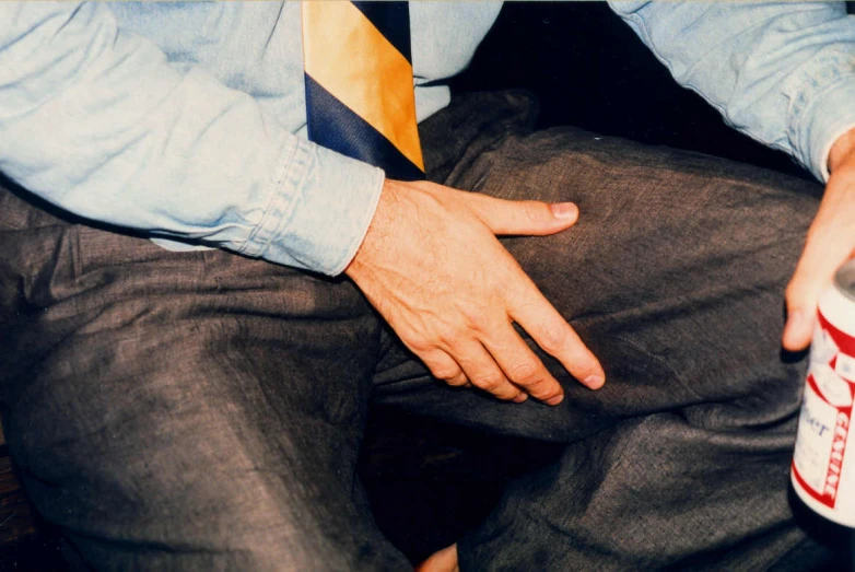 an arm in a tie while seated next to a can of soda