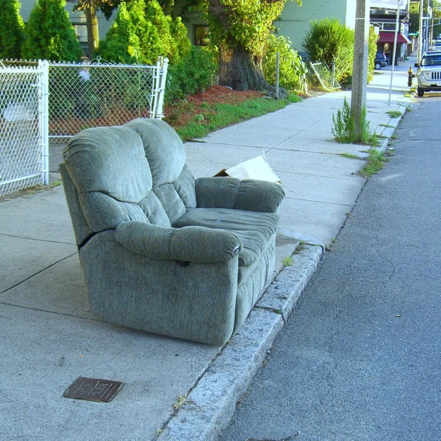 an old recliner on the side of a sidewalk