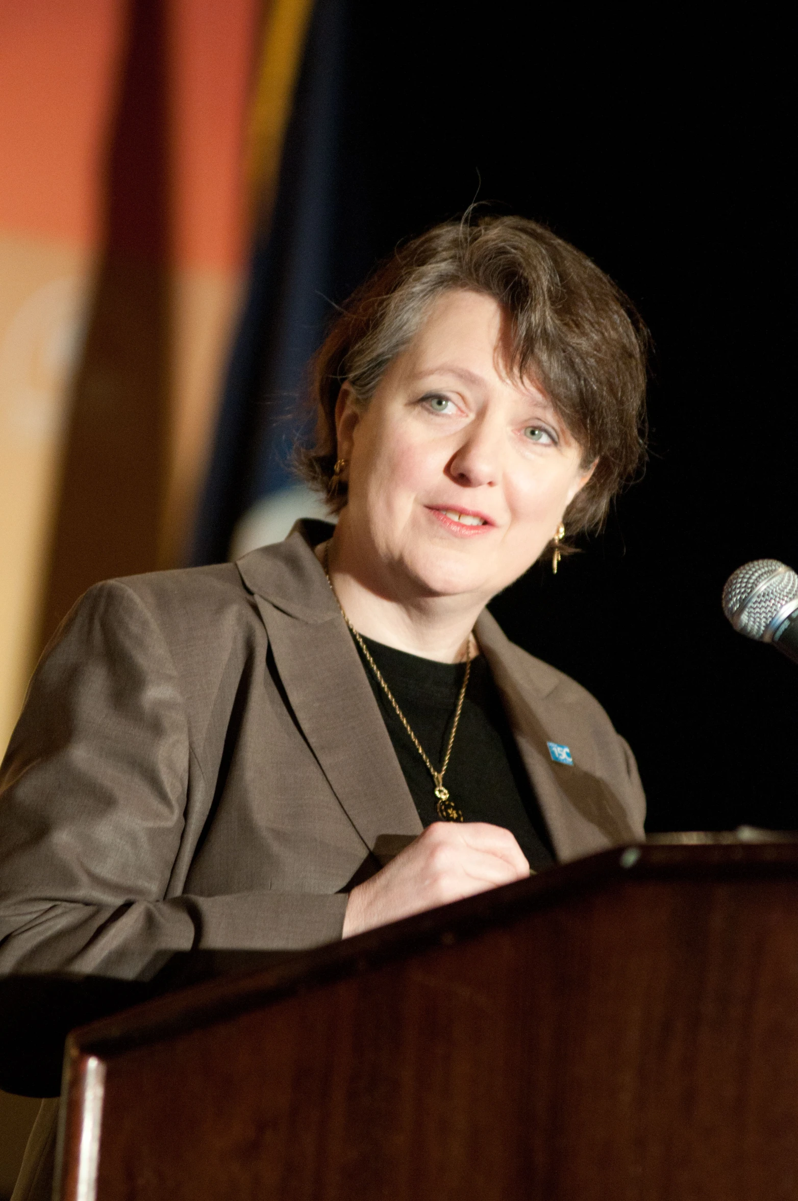 a woman standing at a podium in front of a microphone