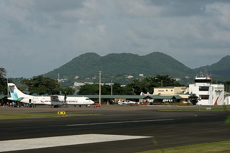 a large airplane sits on the runway near some mountains