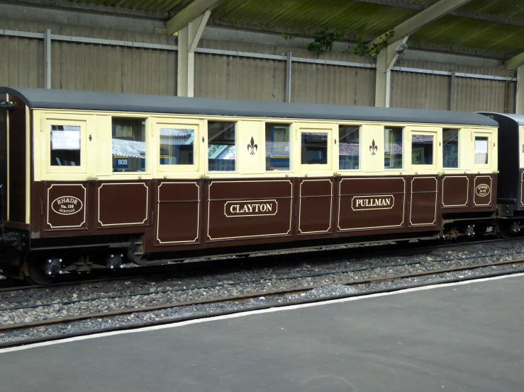 a yellow and brown train engine traveling under a roof