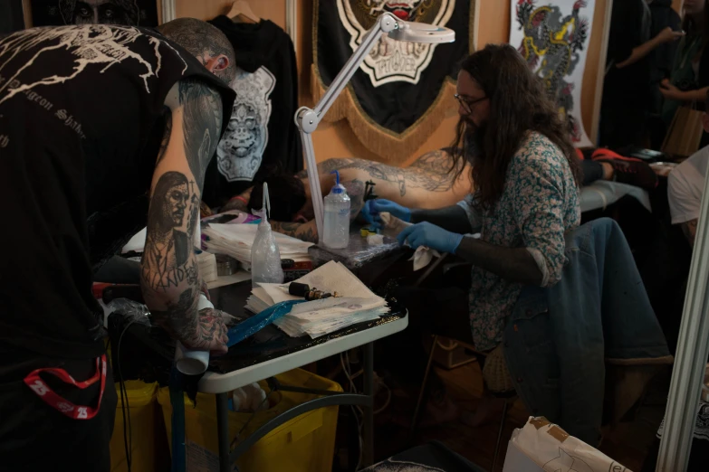 two people doing various tattoos on their bodies