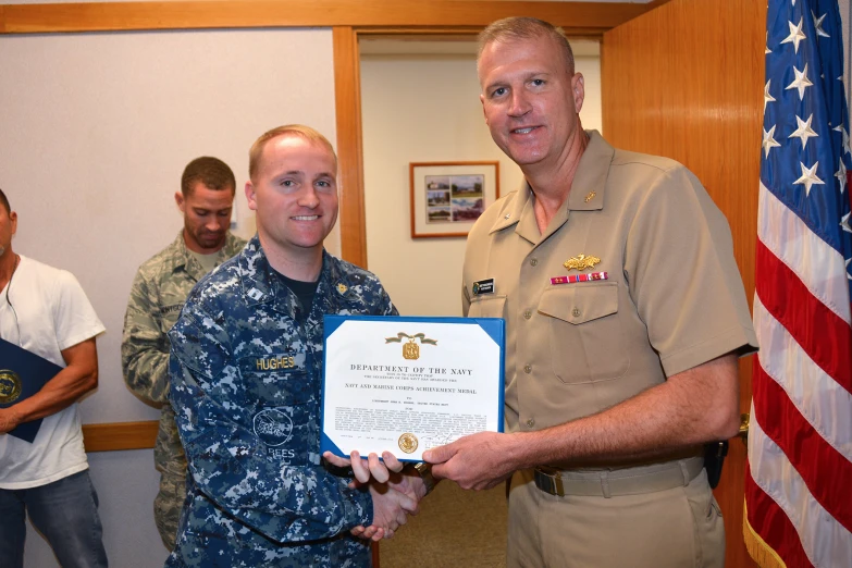 the man in uniform is holding the certificate to a soldier