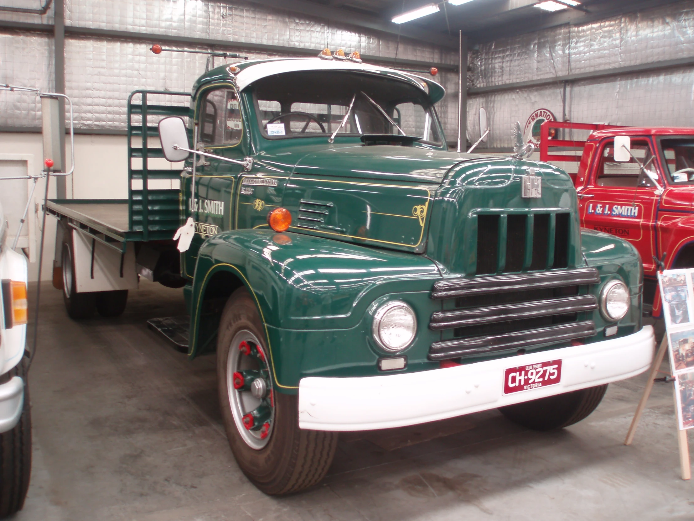 two trucks sitting inside of a building next to other vehicles