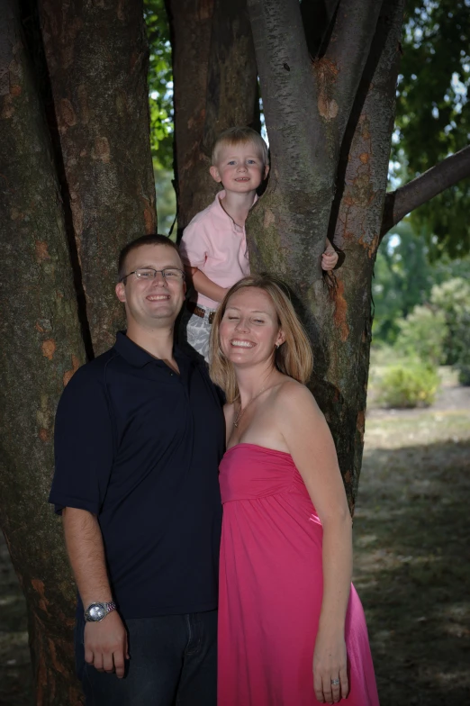 the young man and woman are posing next to a tree with their  in pink