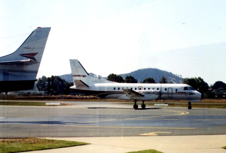 a plane is parked on the runway next to another airplane